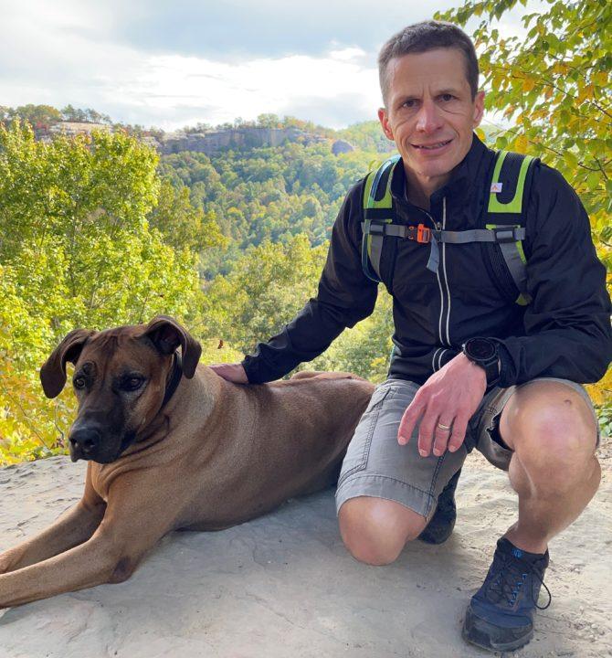 Hiker with his dog on a rock Absorbine Blog